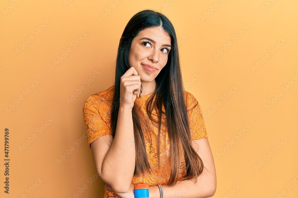 Young hispanic woman wearing casual clothes thinking concentrated about doubt with finger on chin and looking up wondering