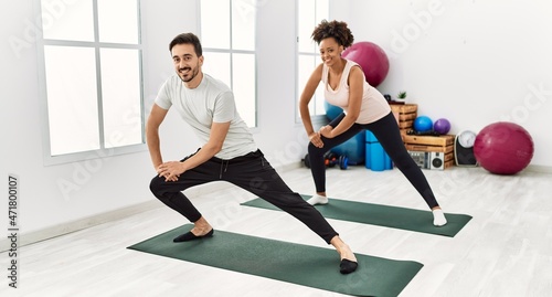 Young african american woman and hispanic man exercising at pilates room  stretching body and doing yoga pose  training strength and balance