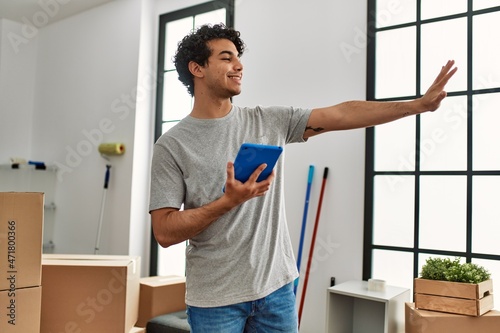Young hispanic man using touchpad moving at new home.