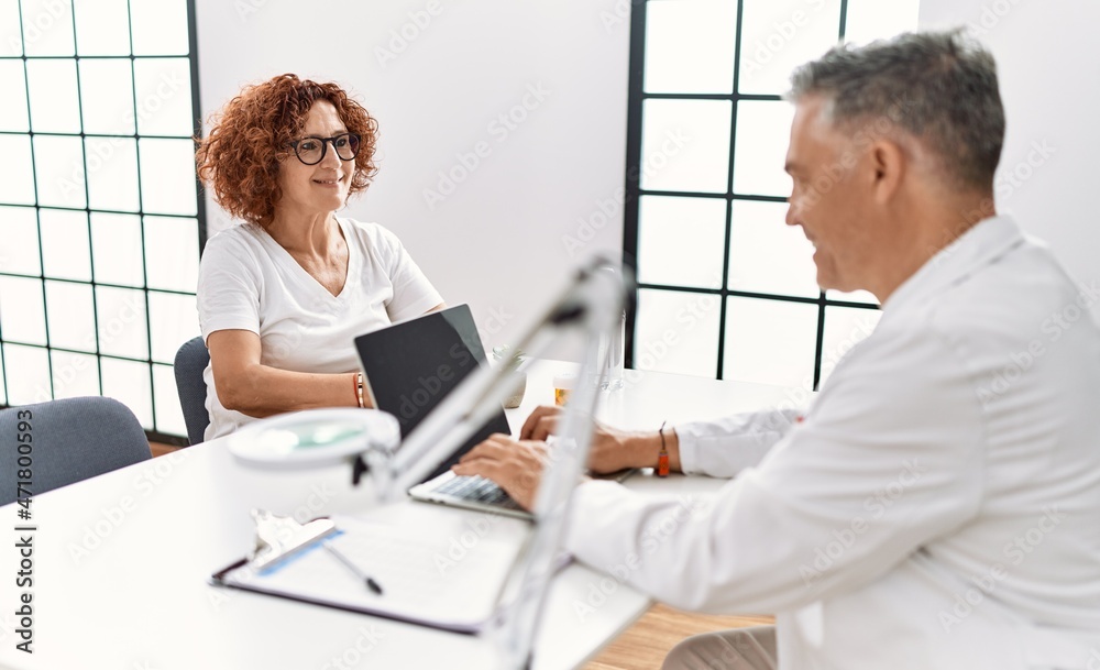 Middle age man and woman wearing doctor uniform having medical consultation at clinic Middle age man and woman wearing doctor uniform having medical consultation at clinic
