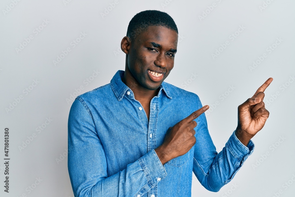 Young african american man wearing casual clothes smiling and looking at the camera pointing with two hands and fingers to the side. Young african american man wearing casual clothes smiling and looking at the camera pointing with two hands and fingers to the side.