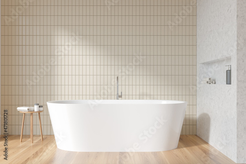 Light bathroom interior with bathtub on parquet floor  table with gels