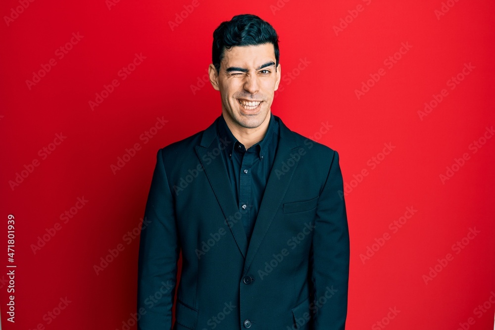 Obraz premium Handsome hispanic man wearing business clothes winking looking at the camera with sexy expression, cheerful and happy face.