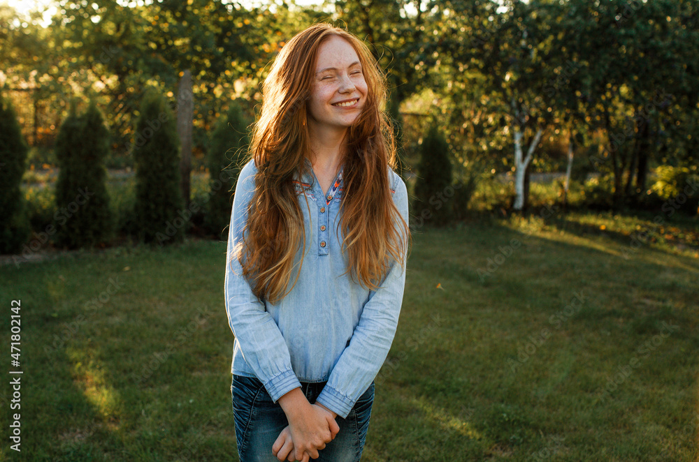 Portrait of a beautiful teenage model girl with red hair against the background of nature in sunlight. Portrait of a beautiful teenage model girl with red hair against the background of nature in sunlight.