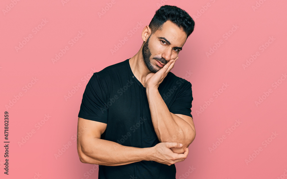 Hispanic man with beard wearing casual black t shirt thinking looking tired and bored with depression problems with crossed arms. Hispanic man with beard wearing casual black t shirt thinking looking tired and bored with depression problems with crossed arms.
