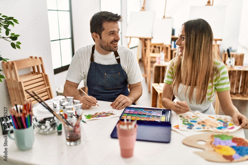 Fototapeta premium Two students smiling happy painting sitting on the table at art school.