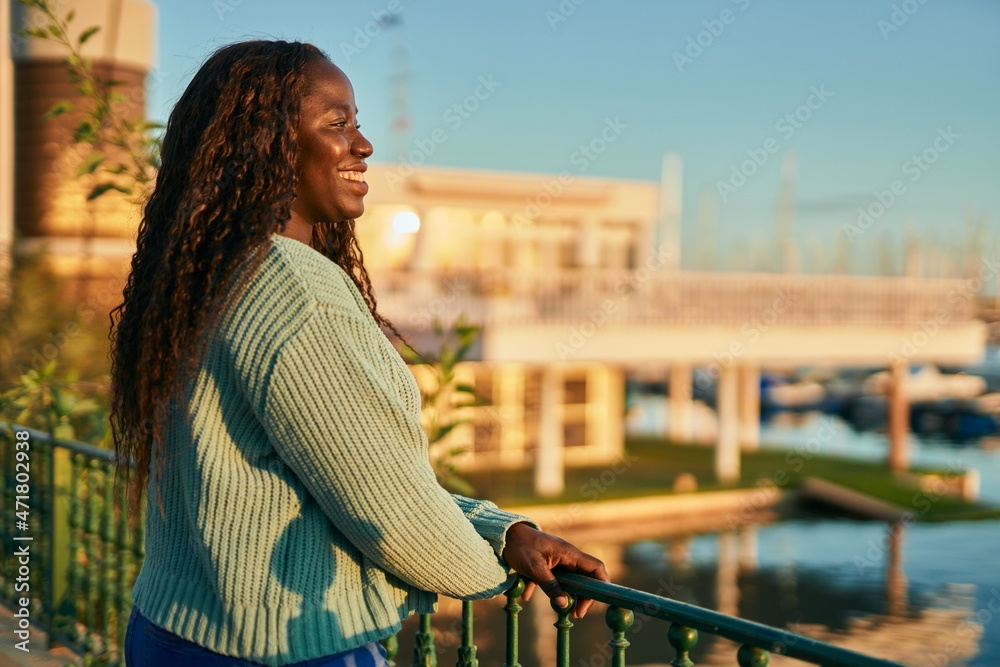Young african woman smiling happy by marina port