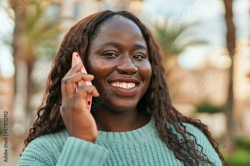 Young african woman smiling happy speaking on the phone at the city
