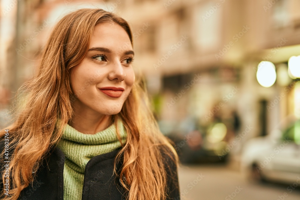 Young blonde girl smiling happy standing at the city.