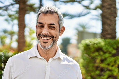 Middle age grey-haired man smiling happy standing at the city.