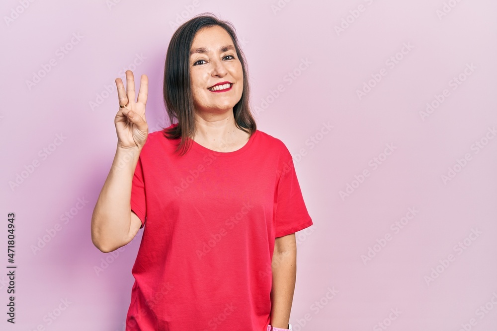 Middle age hispanic woman wearing casual clothes showing and pointing up with fingers number three while smiling confident and happy. Middle age hispanic woman wearing casual clothes showing and pointing up with fingers number three while smiling confident and happy.