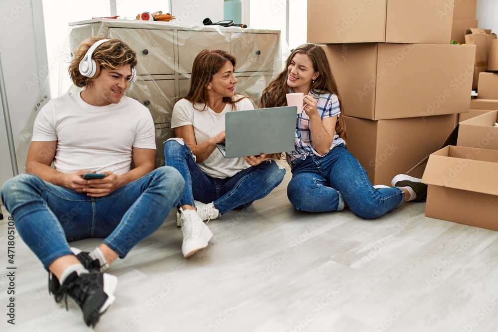 Mother and couple using smartphone and laptop sitting on the floor at home Mother and couple using smartphone and laptop sitting on the floor at home