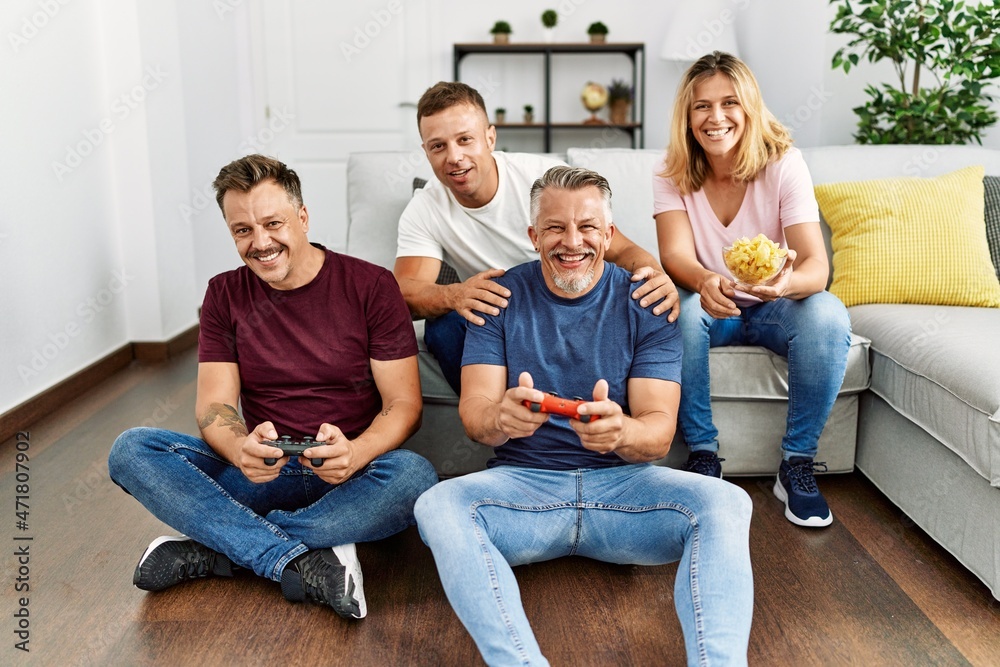 Group of middle age friends smiling happy playing video game at home. Group of middle age friends smiling happy playing video game at home.