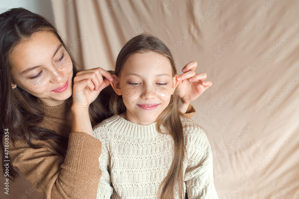 sisters having fun on beige color textile background sisters having fun on beige color textile background