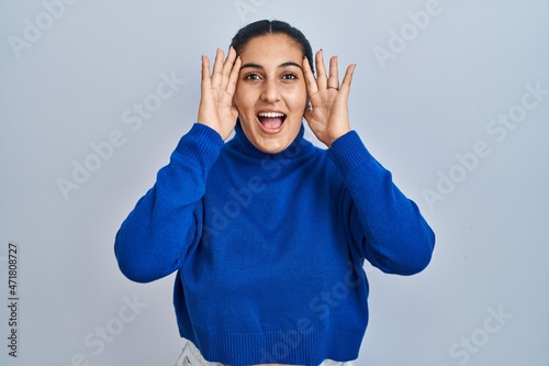 Фотография Young hispanic woman standing over isolated background smiling cheerful playing peek a boo with hands showing face