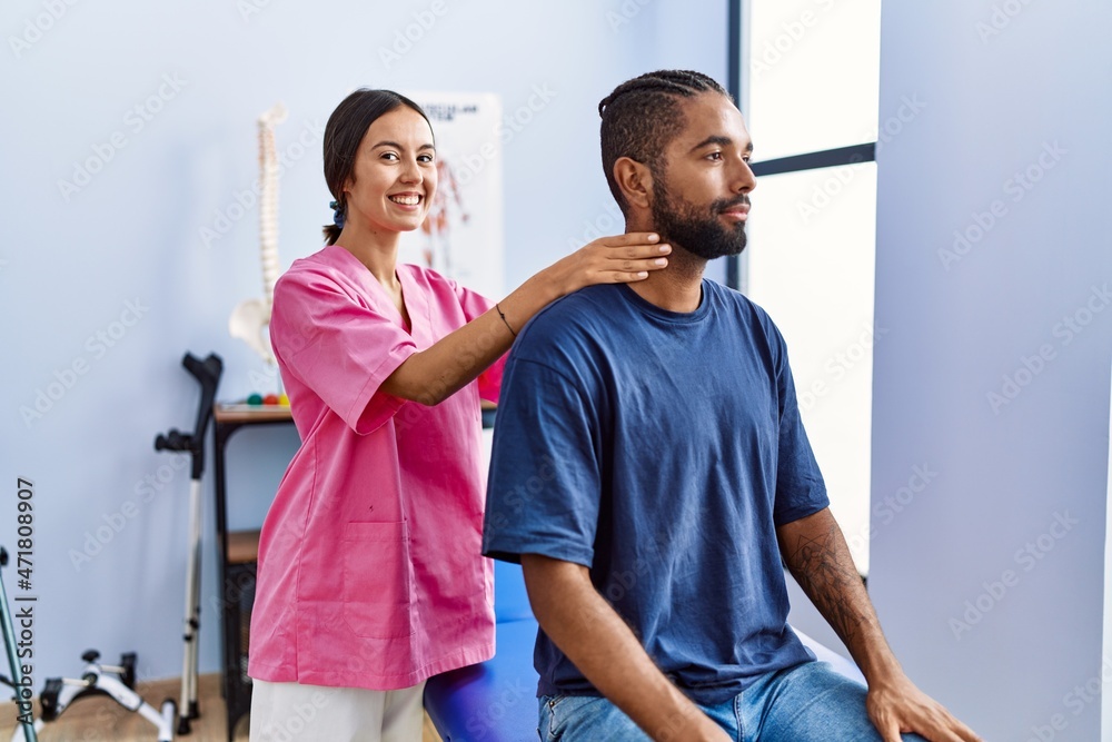 Man and woman wearing physiotherapist uniform having rehab session massaging neck at physiotherpy clinic Man and woman wearing physiotherapist uniform having rehab session massaging neck at physiotherpy clinic