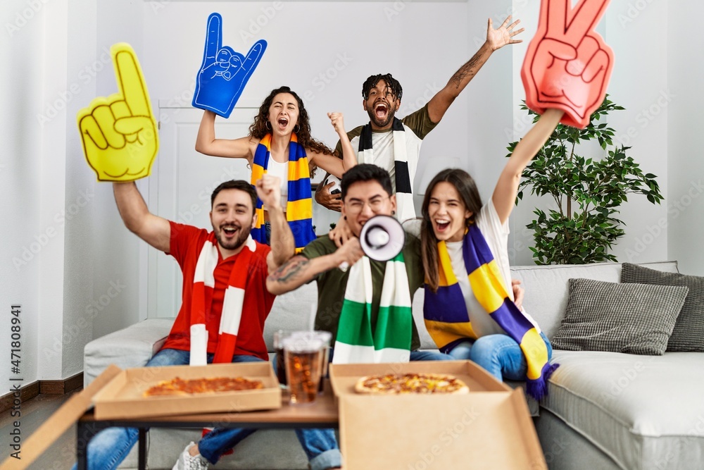 Obraz premium Group of young friends watching and supporting soccer match at home.