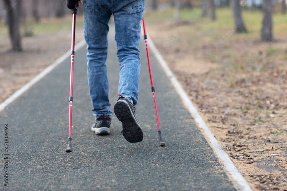 Young man walks with Scandinavian nordic walking sticks. Healthy lifestyle Young man walks with Scandinavian nordic walking sticks. Healthy lifestyle