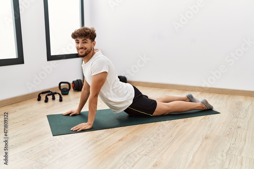 Young arab man smiling confident stretching at sport center