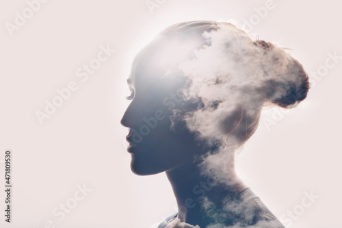 Psychology and caucasian woman mental health concept. Multiple exposure clouds and sun on female head silhouette. photo