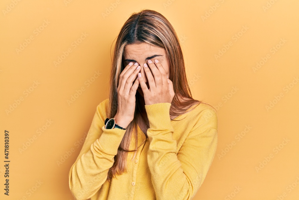 Beautiful hispanic woman wearing casual yellow sweater rubbing eyes for fatigue and headache, sleepy and tired expression. vision problem Beautiful hispanic woman wearing casual yellow sweater rubbing eyes for fatigue and headache, sleepy and tired expression. vision problem