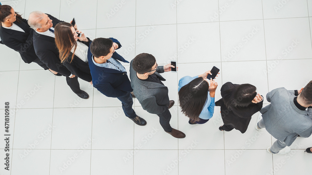 Fototapeta premium top view. a group of business people looking at their smartphon screens.