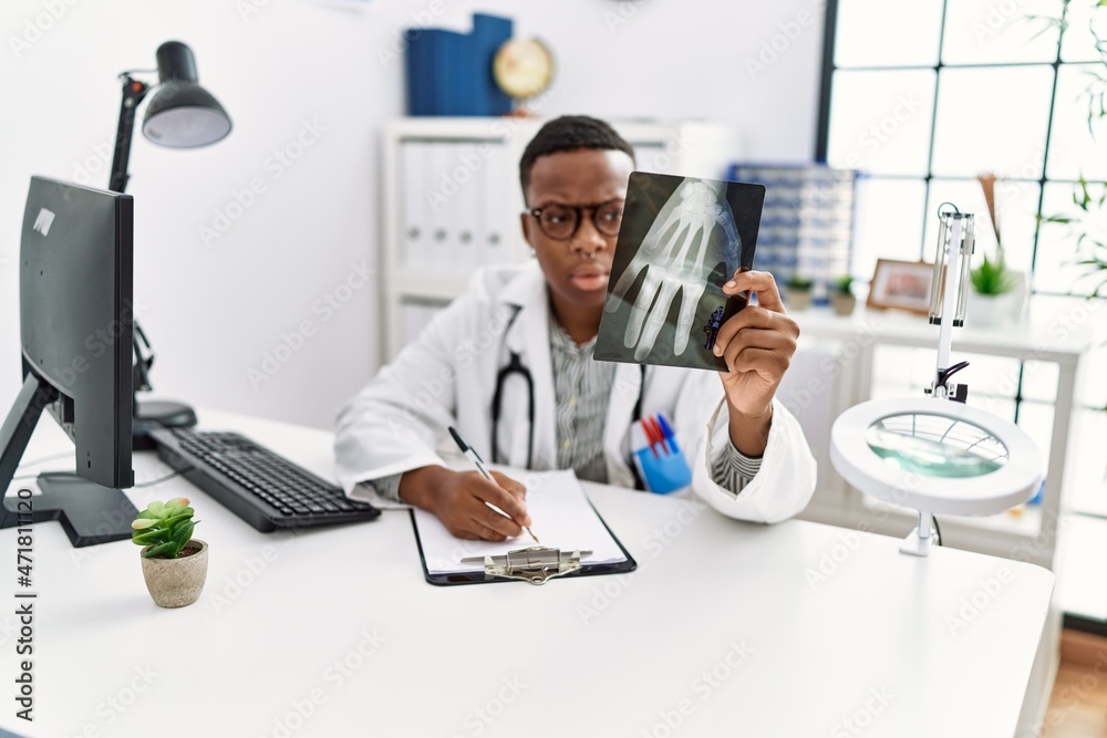 Young african man working as doctor looking at hand xray at medical clinic Young african man working as doctor looking at hand xray at medical clinic