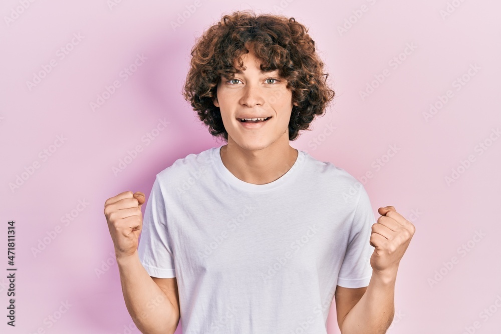 Handsome young man wearing casual white t shirt celebrating surprised and amazed for success with arms raised and open eyes. winner concept. Handsome young man wearing casual white t shirt celebrating surprised and amazed for success with arms raised and open eyes. winner concept.