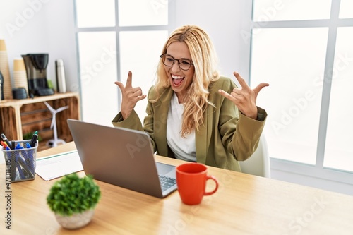 Φωτογραφία Beautiful blonde woman working at the office with laptop shouting with crazy expression doing rock symbol with hands up