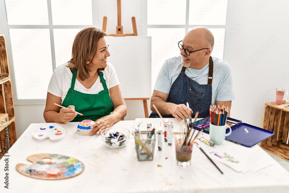 Middle age hispanic painter couple smiling happy painting at art studio. Middle age hispanic painter couple smiling happy painting at art studio.