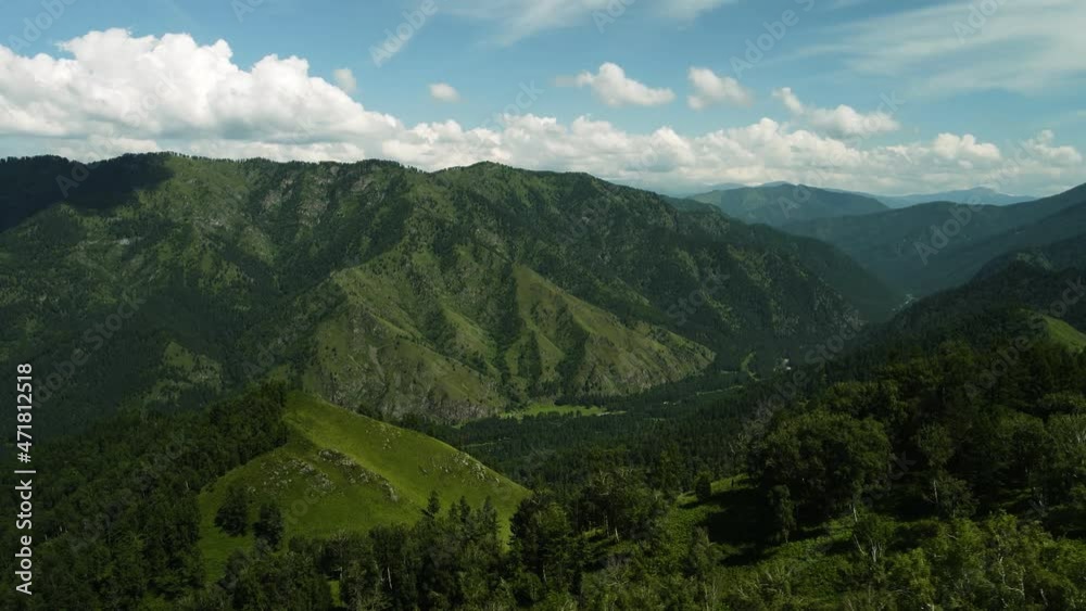 Green mountain expanses against the background of a blue sky. Light clouds reflect sunlight in the summer. Mountain landscapes Green mountain expanses against the background of a blue sky. Light clouds reflect sunlight in the summer. Mountain landscapes