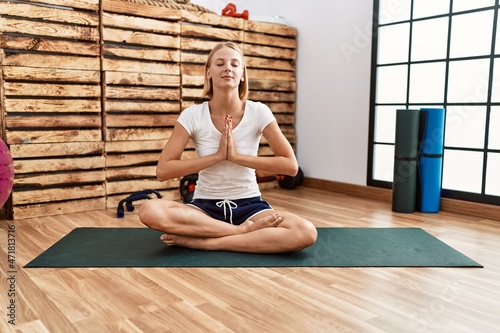 Young blonde woman training yoga at sport center