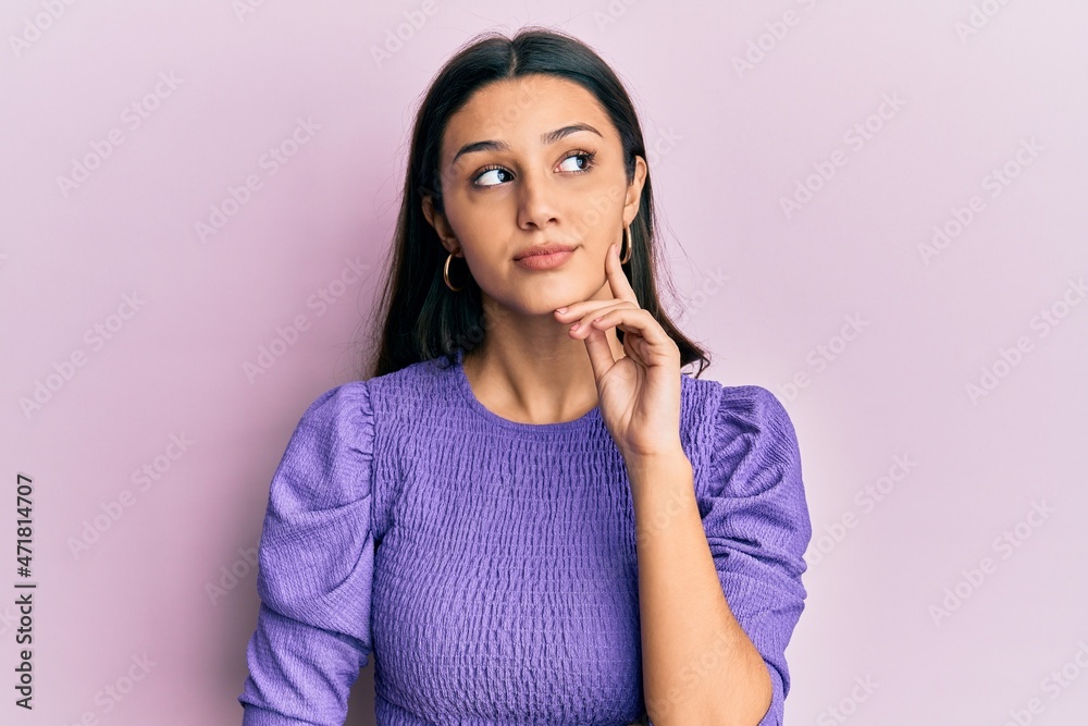 Young hispanic woman wearing casual clothes thinking concentrated about doubt with finger on chin and looking up wondering Young hispanic woman wearing casual clothes thinking concentrated about doubt with finger on chin and looking up wondering