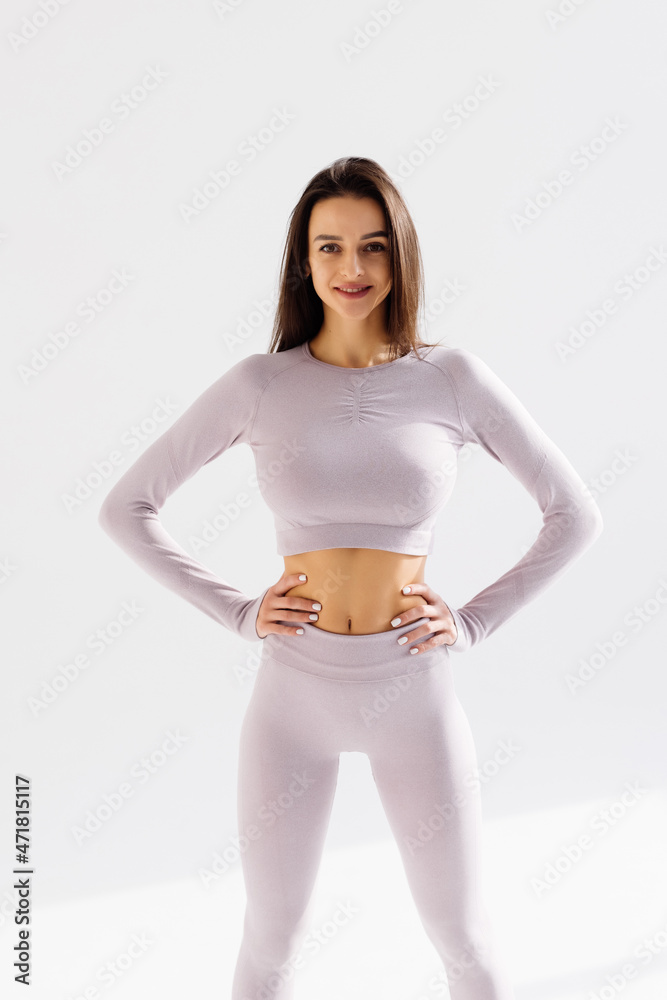 Fitness young pretty woman in black leggings and tank top posing with hands on hips isolated on white studio background Fitness young pretty woman in black leggings and tank top posing with hands on hips isolated on white studio background