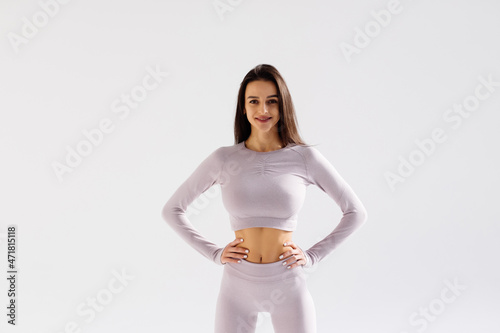 Fitness young pretty woman in black leggings and tank top posing with hands on hips isolated on white studio background photo