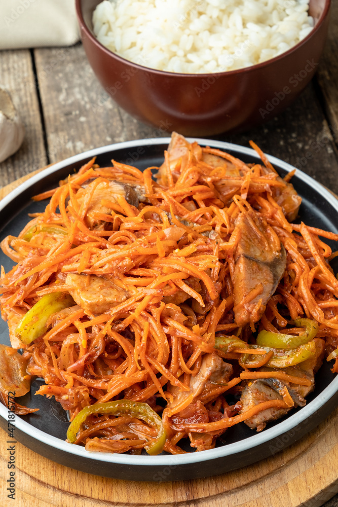 Korean salad of fish and carrots with onions, garlic. Fish he in Korean. Wooden background. Korean salad of fish and carrots with onions, garlic. Fish he in Korean. Wooden background.