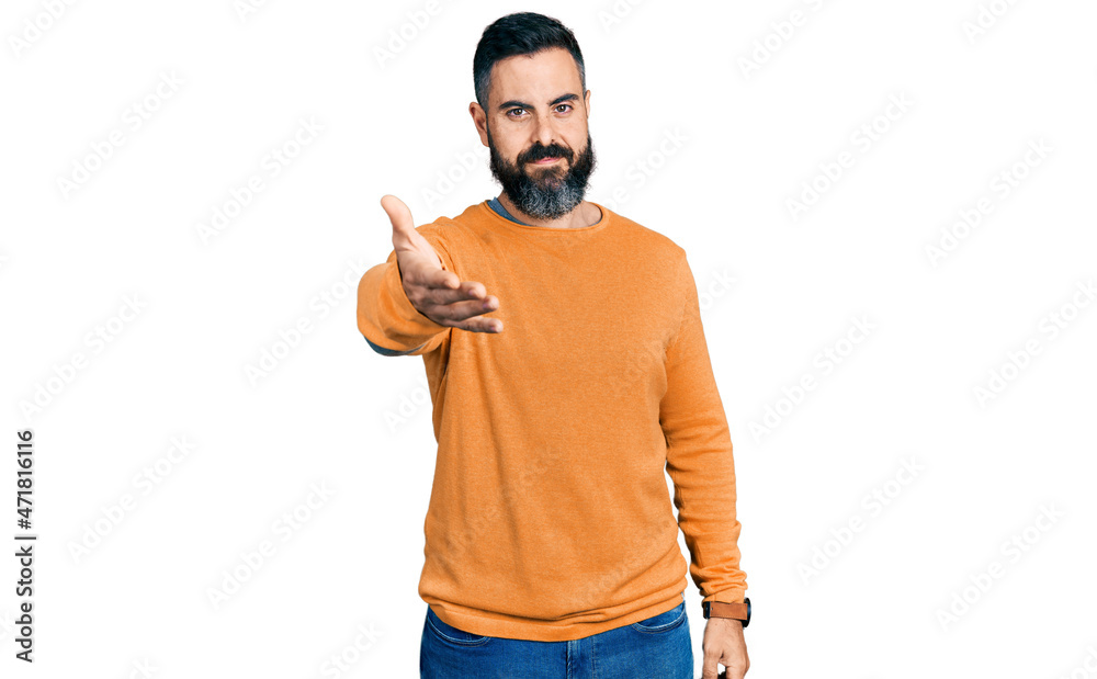 Hispanic man with beard wearing casual winter sweater smiling cheerful offering palm hand giving assistance and acceptance. Hispanic man with beard wearing casual winter sweater smiling cheerful offering palm hand giving assistance and acceptance.
