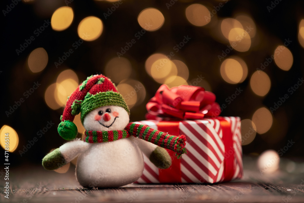 funny snowman and a box with Christmas gifts on a festive background.