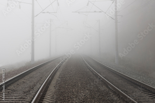 A railroad going into fog in the middle of an autumn landscape. Rails lost in the distance and disappearing into the fog.