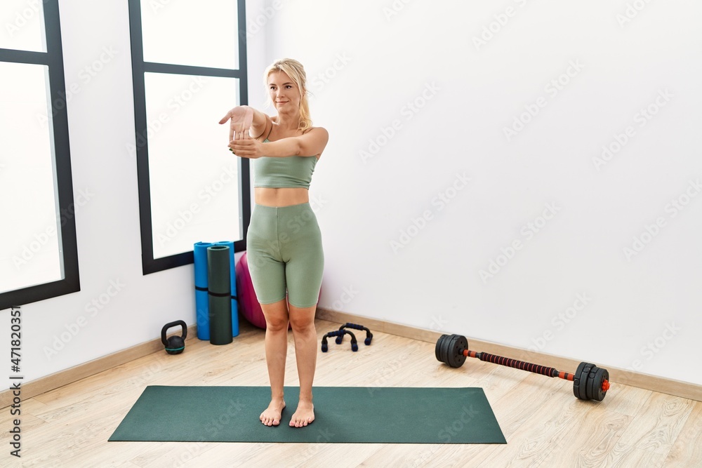 Young blonde girl smiling happy stretching arms at sport center. Young blonde girl smiling happy stretching arms at sport center.