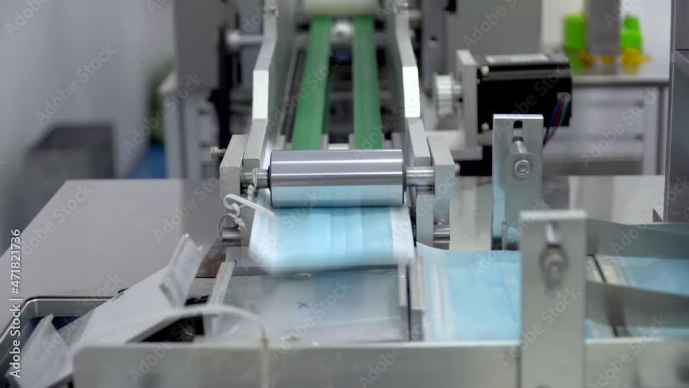 The process of manufacturing line production medical face mask with automatic machinery in an industrial factory . Shortages during the coronavirus pandemic or covid-19 outbreak The process of manufacturing line production medical face mask with automatic machinery in an industrial factory . Shortages during the coronavirus pandemic or covid-19 outbreak