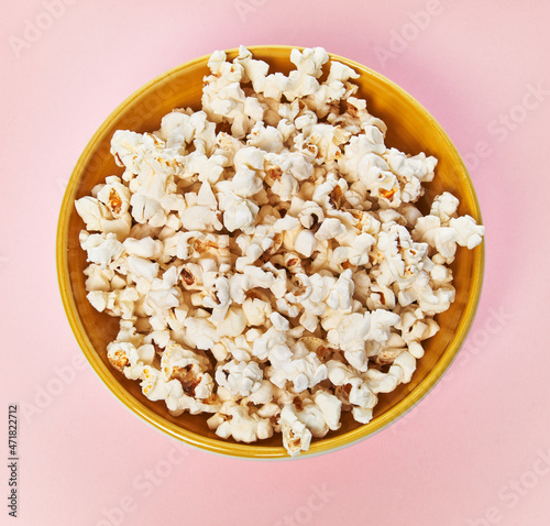  Bowl of salty popcorns on a pink background