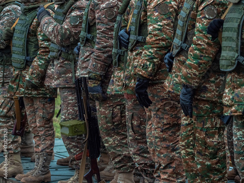 Armed soldiers in camouflage military uniform. Soldiers in formation. Full combat gear. 