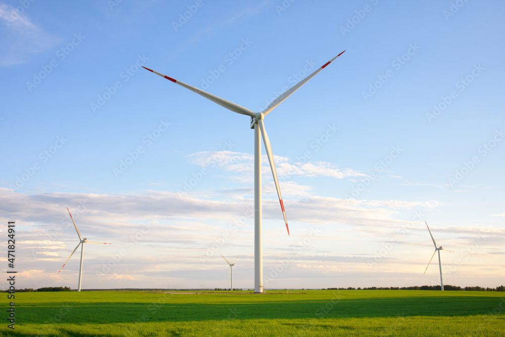 View on alternative energy windmills in a windpark in Ulyanovsk in front of a blue sky. Windmills for electric power production. View on alternative energy windmills in a windpark in Ulyanovsk in front of a blue sky. Windmills for electric power production.