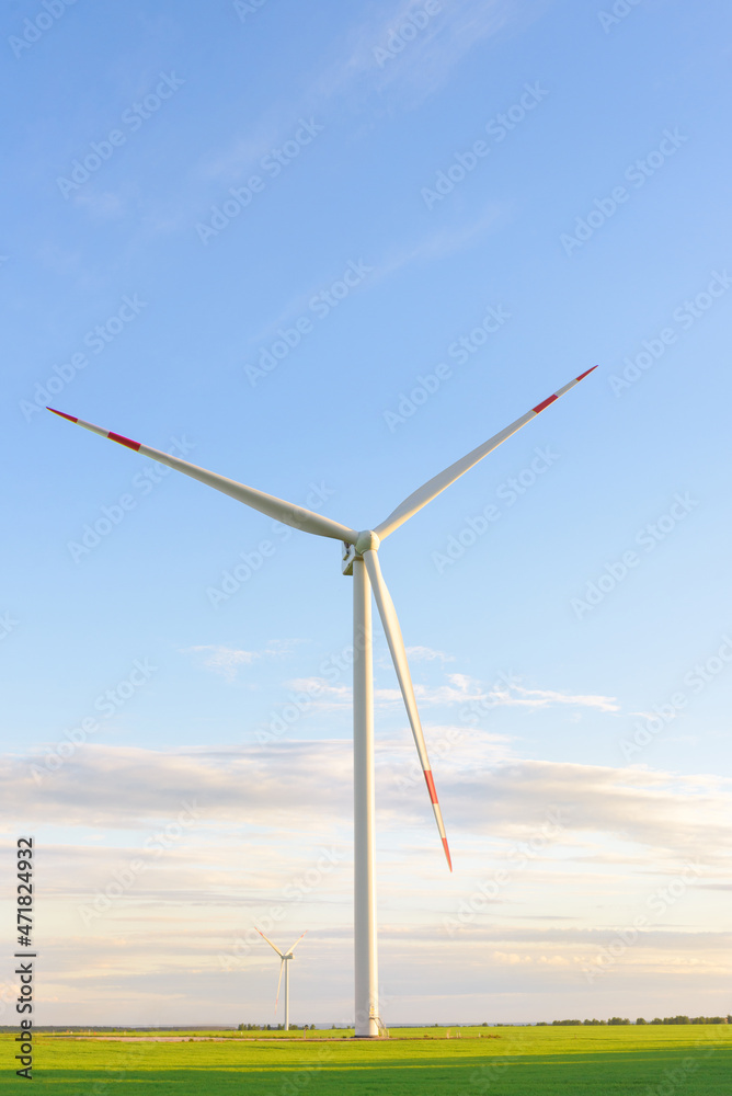 View on alternative energy windmills in a windpark in Ulyanovsk in front of a blue sky. Windmills for electric power production. View on alternative energy windmills in a windpark in Ulyanovsk in front of a blue sky. Windmills for electric power production.
