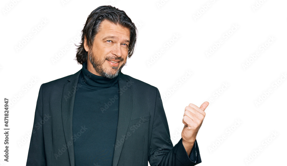 Middle age handsome man wearing business clothes smiling with happy face looking and pointing to the side with thumb up. Middle age handsome man wearing business clothes smiling with happy face looking and pointing to the side with thumb up.