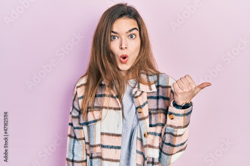 Young caucasian girl wearing casual clothes surprised pointing with hand finger to the side, open mouth amazed expression.