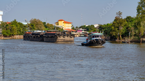 Tug boats tow barges on river in Thailand