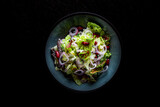 Mediterranean red beans salad with mix of lettuce leaves and onion on black plate