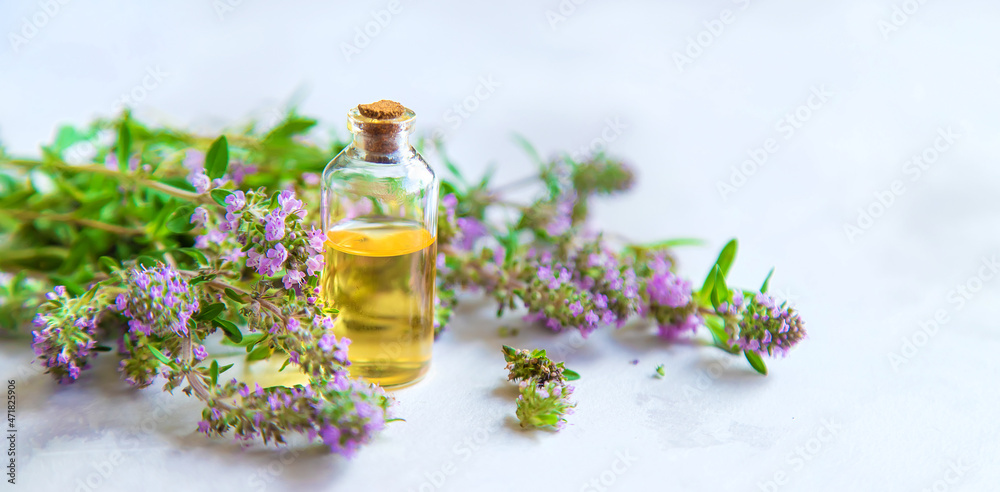 Thyme essential oil in a small bottle. Selective focus.